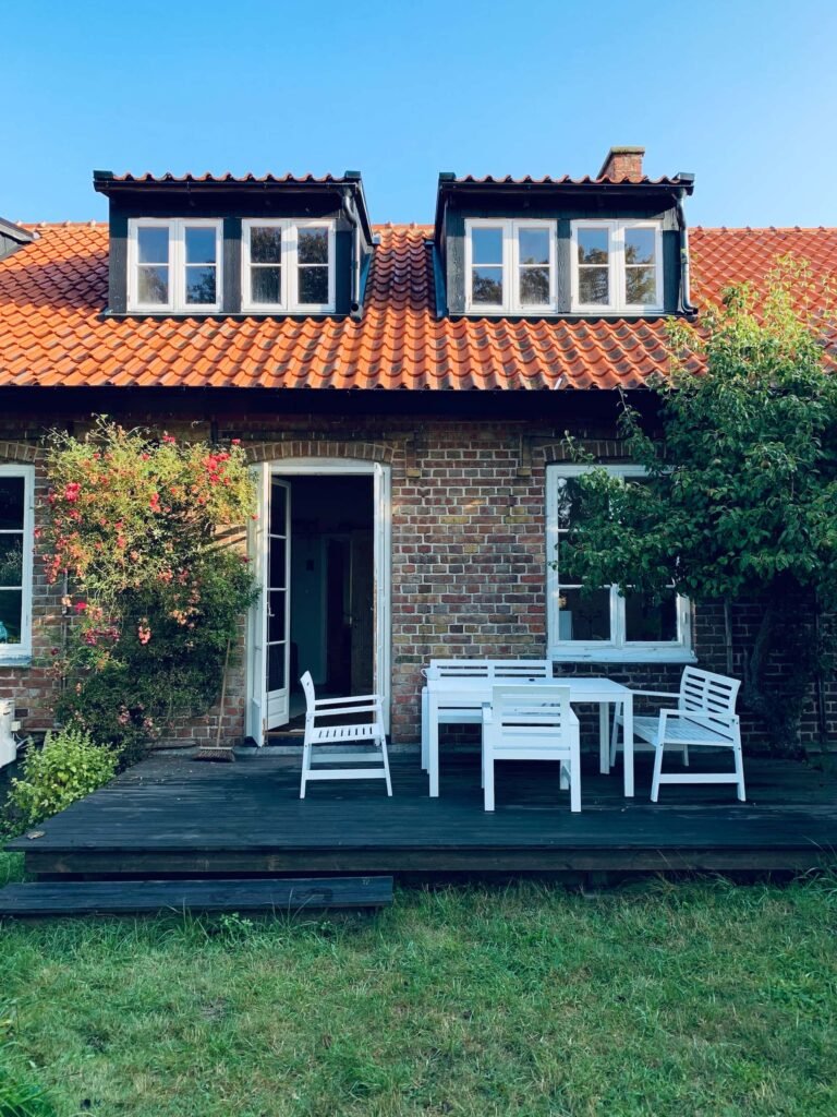 Trending tile designs for Gurgaon farmhouse exteriors with rustic brick walls, terracotta roof, and outdoor stone flooring.