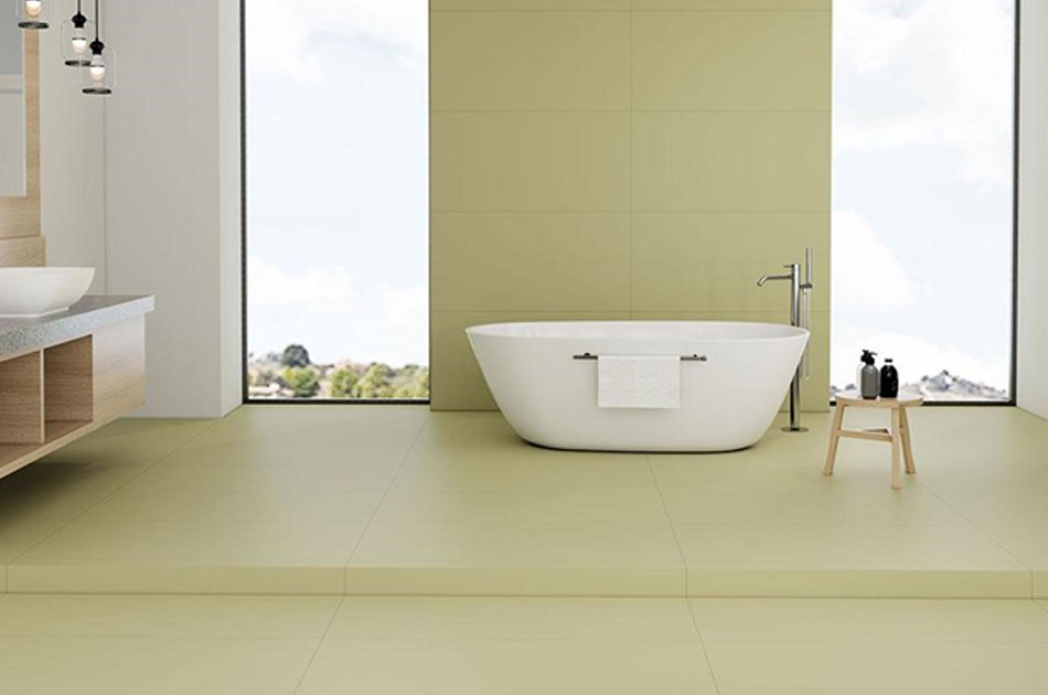 Modern bathroom interior featuring large-format vitrified tiles on the floor and walls, surrounding a freestanding bathtub in a minimalist luxury design.