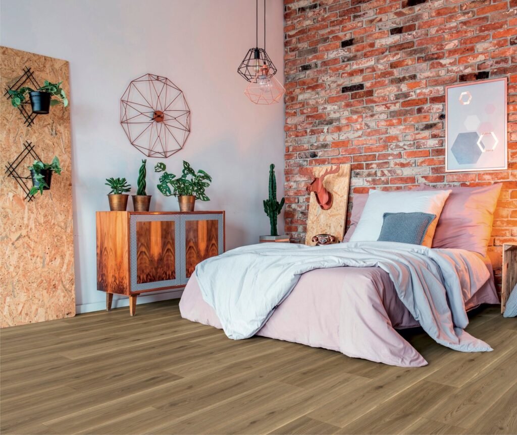 Cozy modern bedroom with exposed brick wall, neutral bedding, indoor plants, and premium wooden floor tiles for a warm, rustic aesthetic.