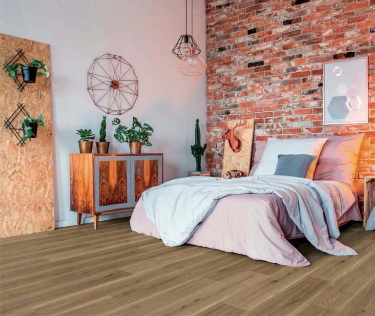 Cozy modern bedroom with exposed brick wall, neutral bedding, indoor plants, and premium wooden floor tiles for a warm, rustic aesthetic.