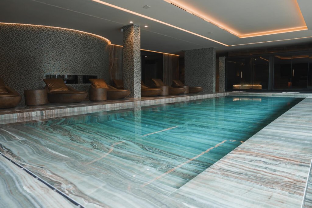 Minimalist poolside tiles in soft stone shades offering a seamless rooftop pool design with modern elegance
