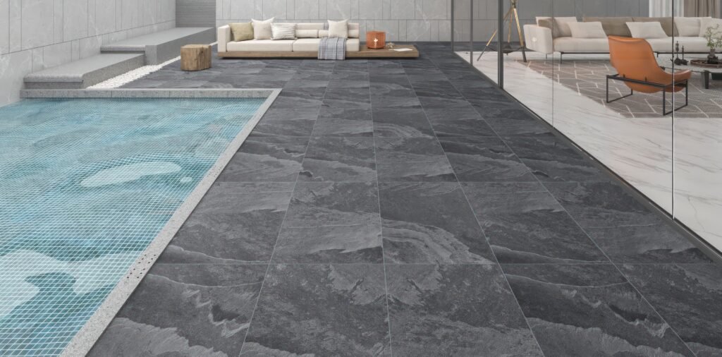 Luxury poolside patio with dark textured flooring demonstrating durable Ceramic Tile Design Ideas for seamless indoor-outdoor spaces in modern villas and premium residences.